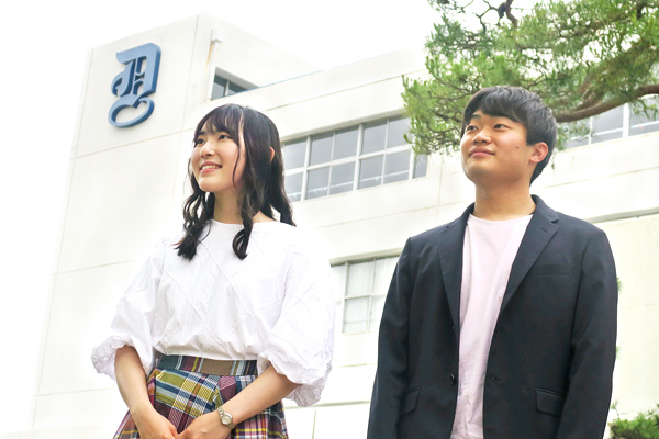 校舎の前に立つ増田さんと井上くん