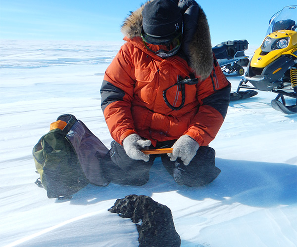 南極で、見つけた隕石のサイズを計測する三河内先生。