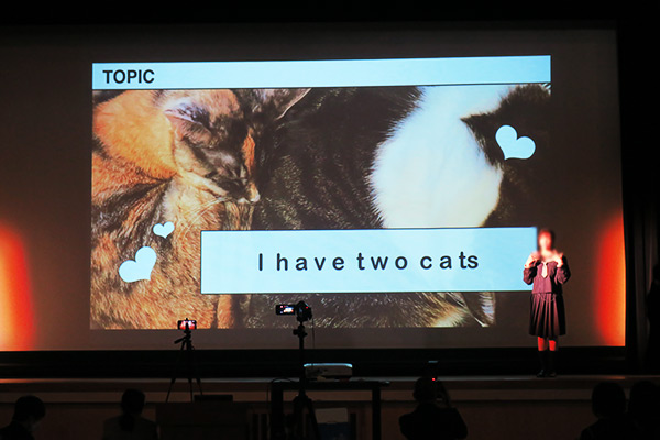 猫について英語でプレゼンテーションする女子学生の写真